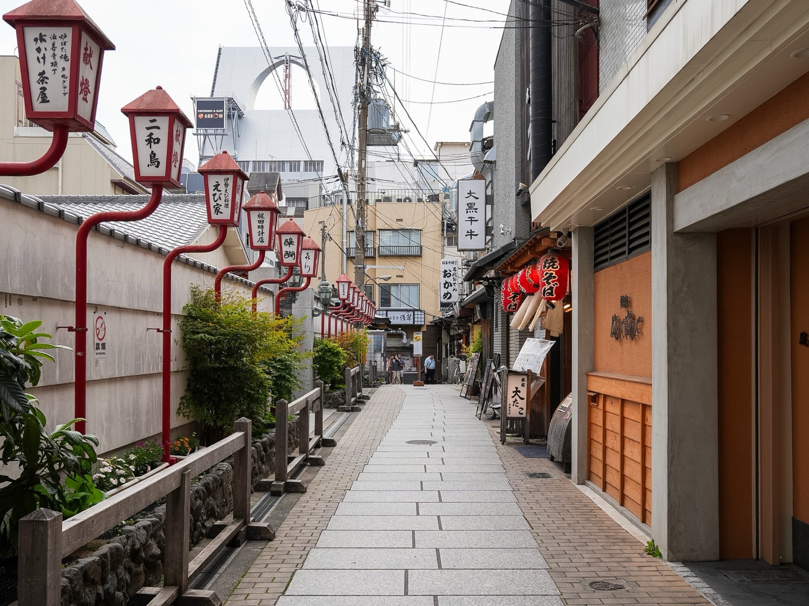 Red lanterns line a stone paved alley in Hozenji Yokocho