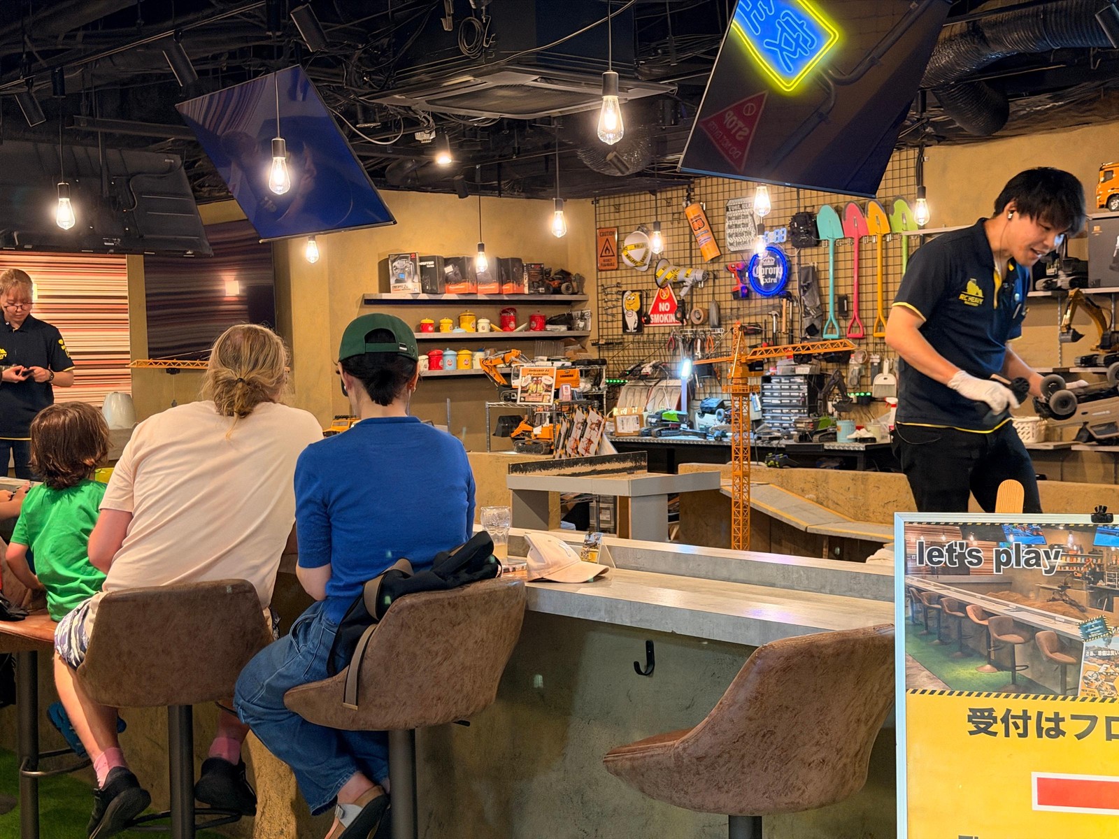 Guests at the counter of the RC cafe watching a staff member handle a radio-controlled digger