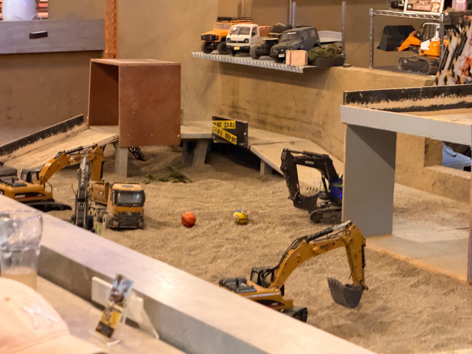 A miniature construction site with radio-controlled excavators and diggers in sand